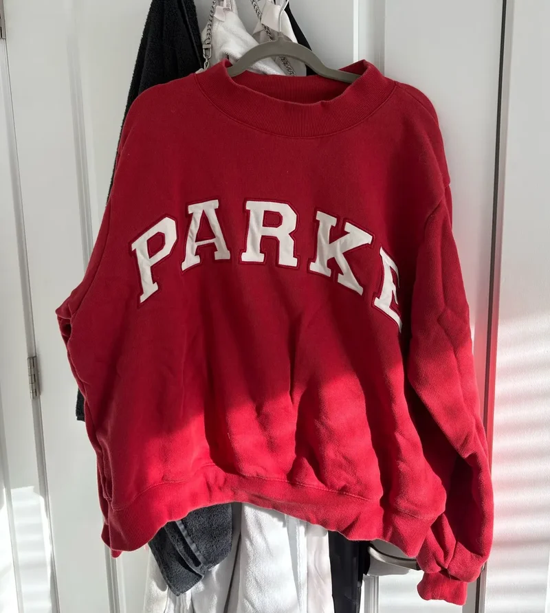 A red Parke sweatshirt hanging on a closet door